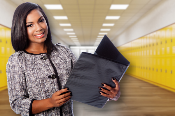 woman holding a folder in a hallway with yellow lockers behind her.