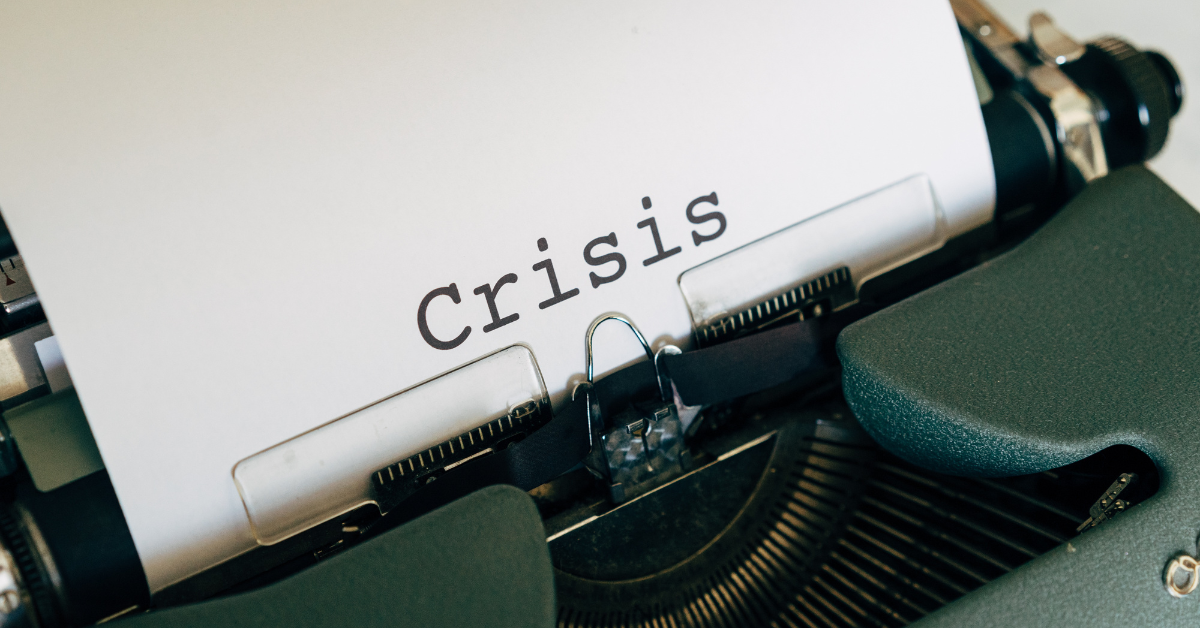 Green typewriter with page in progress, text "Crisis"