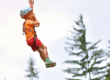 Young boy on zipline in pine trees
