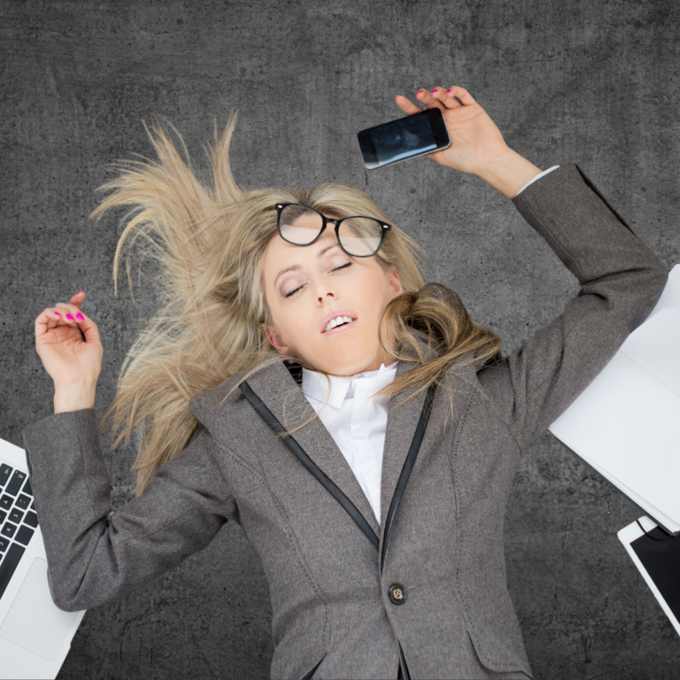 Frazzled professional passed out on the floor with laptop, phone and tablet surrounding her.