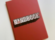 Red handbook symbolizing school district handbooks and the importance of web accessibility when posting online.