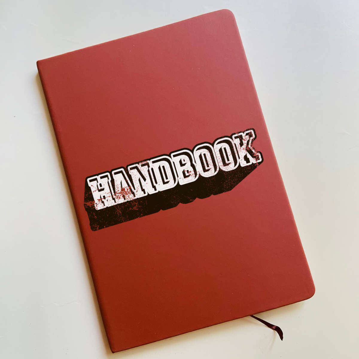 Red handbook symbolizing school district handbooks and the importance of web accessibility when posting online.